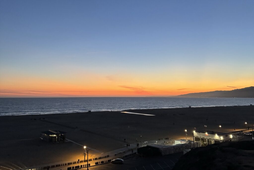 A stunning sunset over Santa Monica Beach is captured in the photograph