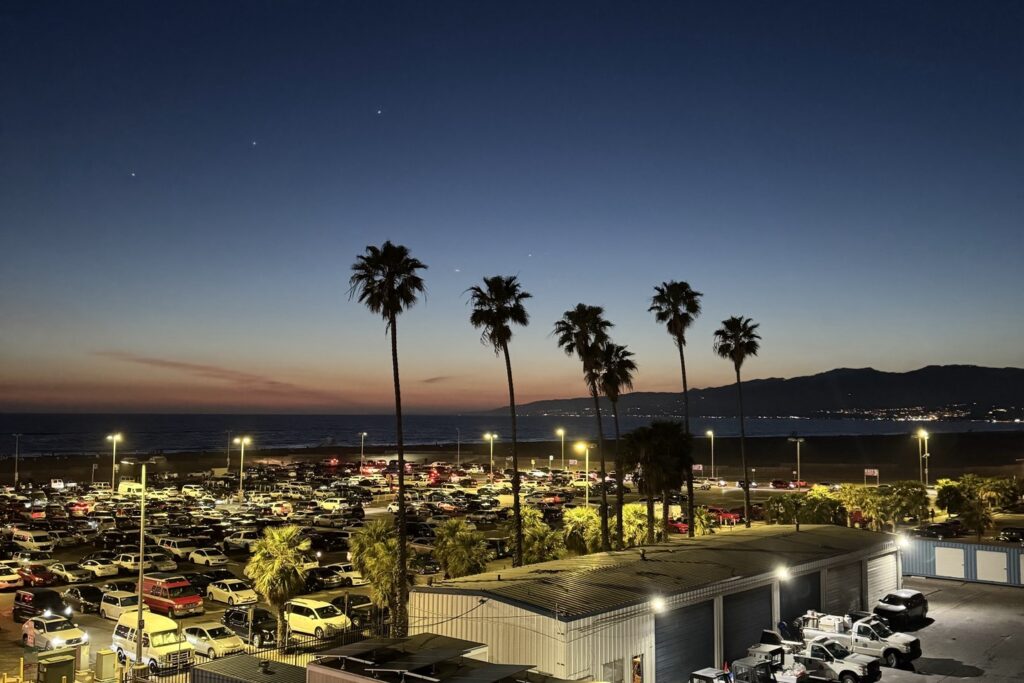 Nighttime view of Santa Monica Beach featuring stars, palm trees, and a sunset